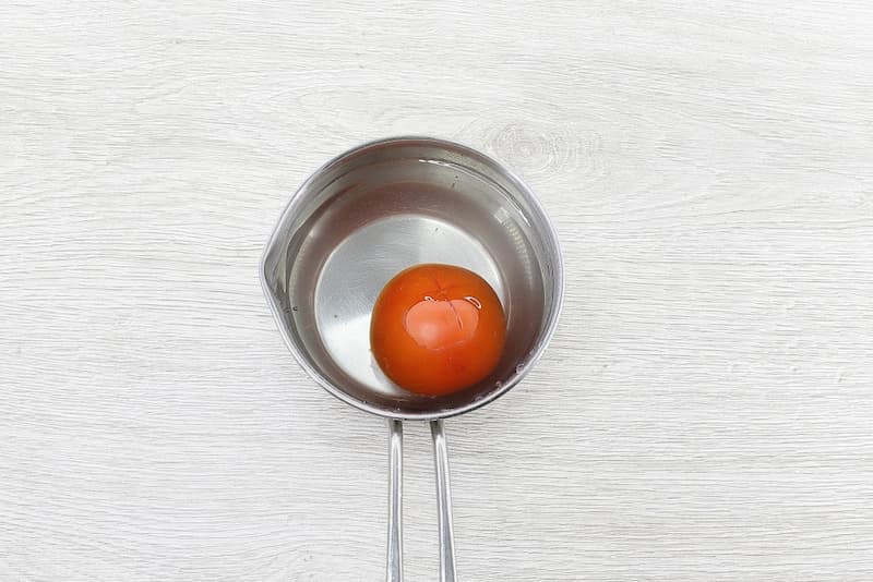 Очистить помидор от кожицы. Сверху сделать неглубокий крестообразный надрез. Вскипятить воду в сотейнике. Опустить помидор буквально на 50–60 секунд в кипящую воду. Переместить в холодную воду на 4–5 минут и потом снять кожицу. 